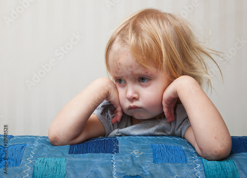 Photo: a sick girl is sitting near the bed a sick girl is sitting near the bed