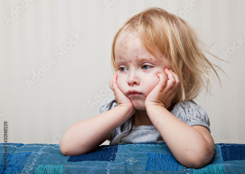 Photo: a sick girl is sitting near the bed a sick girl is sitting near the bed