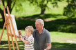 Grandfather and his grandson painting in the garden Grandfather and his grandson painting in the garden
