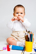 Kid playing with paints and pencils