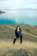 Beautiful girl standing on mountain in front of blue sea and sky