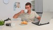 Casual man with a laptop taking his breakfast