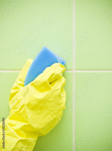 Photo: Hand in yellow protective glove cleaning wall Hand in yellow protective glove cleaning wall