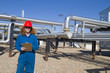 Female gas field operator inspects compressor site Female gas field operator inspects compressor site