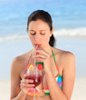 Beautiful woman drinking cocktail on the beach