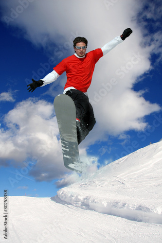 Foto: Snowboarder jumping against blue sky Snowboarder jumping against blue sky