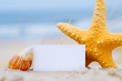 Shells and a blank card on the beach for a message