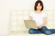 young women on white couch relaxing and using laptop computer