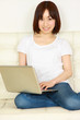 young women on white couch relaxing and using laptop computer