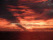 Photo: Dramatic Red light shines through the clouds as the sunsets over Dramatic Red light shines through the clouds as the sunsets over