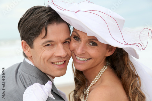 Photo: Portrait of happy married couple at the beach Portrait of happy married couple at the beach