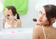 Portrait of attractive young adult woman applying blusher Portrait of attractive young adult woman applying blusher