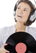 happy brunette in headphones with vinyl record over white