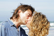 Photo: Young couple in love kissing eachother at the beach Young couple in love kissing eachother at the beach