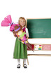 Mädchen mit Schultüte steht am 1. Schultag vor Tafel