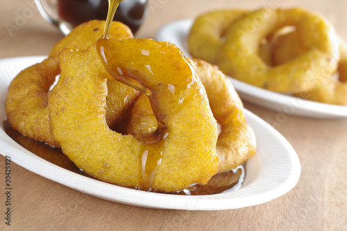 Photo: Pouring syrup on the Peruvian dessert called "picarones" Pouring syrup on the Peruvian dessert called "picarones"