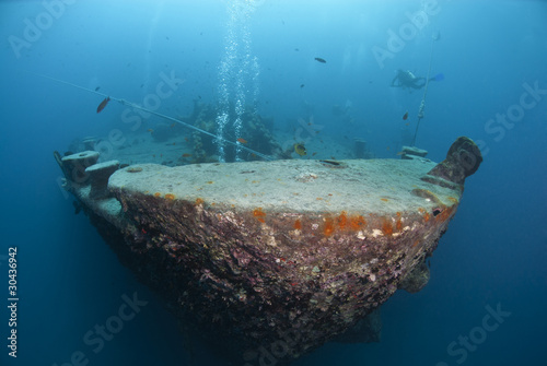 Photo: Silhouettes of scuba divers exploring the bow of a shipwreck. Silhouettes of scuba divers exploring the bow of a shipwreck.