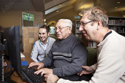 Photo: Volunteers teaching a senior how to use a computer Volunteers teaching a senior how to use a computer