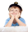Cute dreaming child in captain cap lies on soft sheep fur
