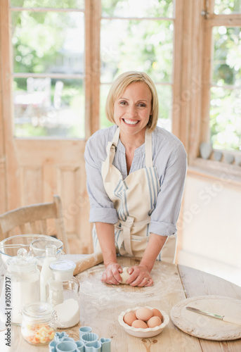 Foto: Smiling woman kneading dough on kitchen table Smiling woman kneading dough on kitchen table