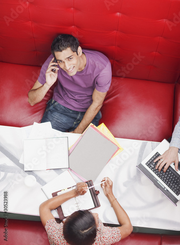 Photo: Smiling businessman talking on cell phone in meeting Smiling businessman talking on cell phone in meeting