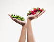 Woman holding handful of strawberries over handful of pea pods