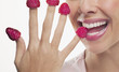 Close up of woman biting raspberries on fingertips