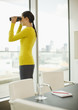 Photo: Businesswoman with binoculars looking out office window Businesswoman with binoculars looking out office window