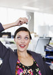 Smiling businesswoman holding light bulb overhead in office