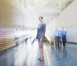Business people rushing past smiling businesswoman in lobby