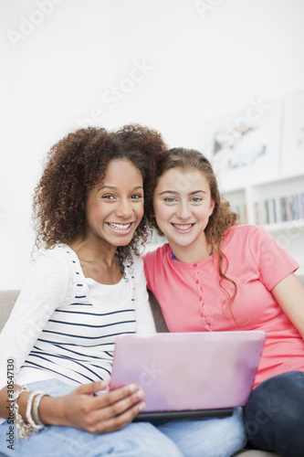 Foto: Smiling teenage girls using laptop together Smiling teenage girls using laptop together