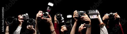 Photo: Raised hands holding different photocameras Raised hands holding different photocameras