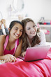 Smiling teenage girls using laptop together