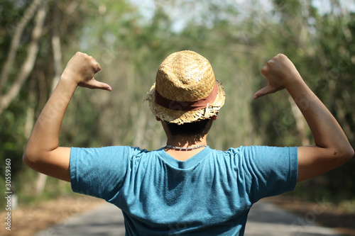 Photo: A man wearing weave hat with self-confident pose among trees. A man wearing weave hat with self-confident pose among trees.