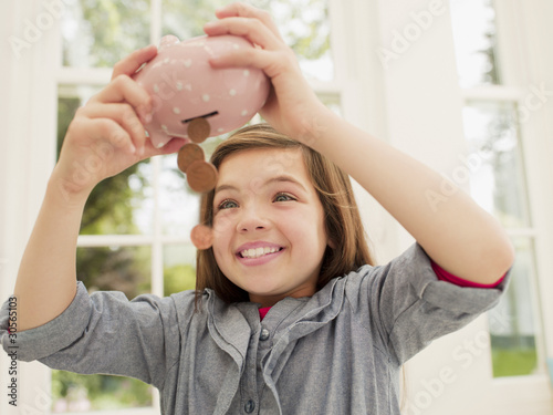 Photo: Excited girl emptying coins from piggy bank Excited girl emptying coins from piggy bank
