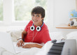Photo: Teenage boy laying on bed with laptop and electronic piano keyboard Teenage boy laying on bed with laptop and electronic piano keyboard