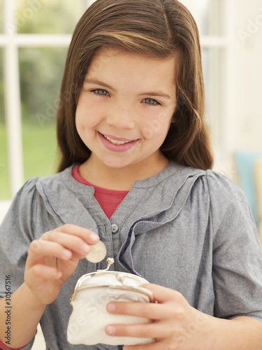 Photo: Smiling girl putting money into coin purse Smiling girl putting money into coin purse
