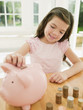 Girl putting coin into piggy bank