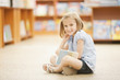 Girl sitting on floor of library with book
