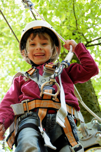 Photo: Mädchen mit Helm beim Klettern im Wald Mädchen mit Helm beim Klettern im Wald