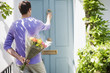 Man holding bouquet of flowers and knocking on door