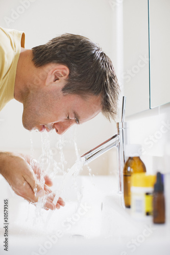 Photo: Man washing face in sink Man washing face in sink