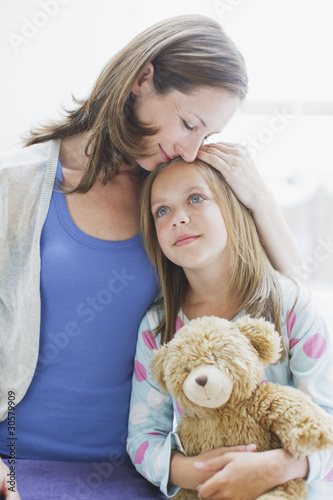 Photo: Mother hugging daughter holding teddy bear Mother hugging daughter holding teddy bear