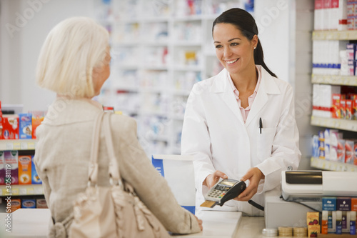 Photo: Pharmacist holding security device for customer in drug store Pharmacist holding security device for customer in drug store