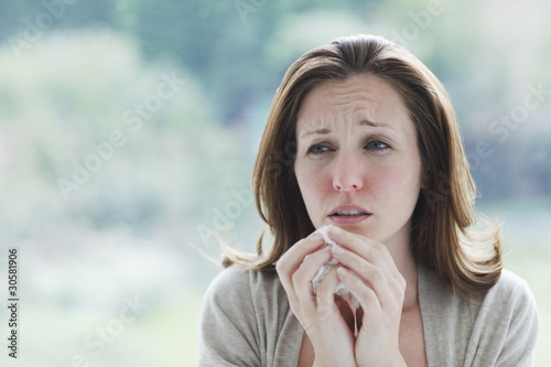 Photo: "Frowning, sick woman holding tissue" "Frowning, sick woman holding tissue"