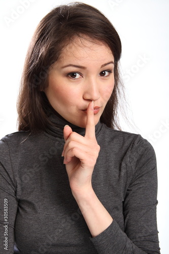 Photo: Quiet please signal by pretty young woman with finger on lips Quiet please signal by pretty young woman with finger on lips