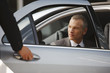 Chauffeur opening car door for businessman