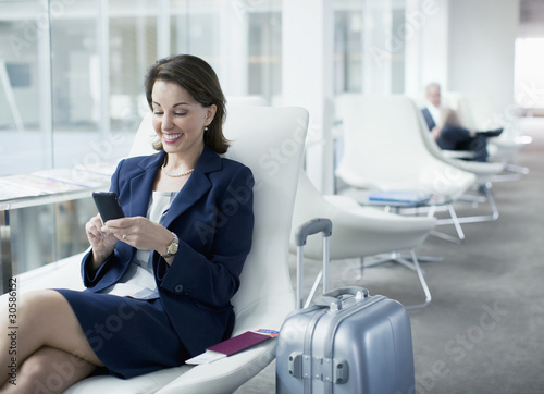 Photo: Businesswoman with luggage sitting in airport waiting area Businesswoman with luggage sitting in airport waiting area