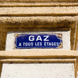 Plaque de rue indiquant la présence de gaz à tous les étages.