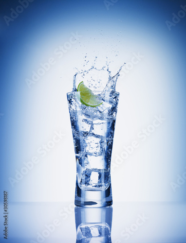 Photo: Lime slice splashing water from glass Lime slice splashing water from glass
